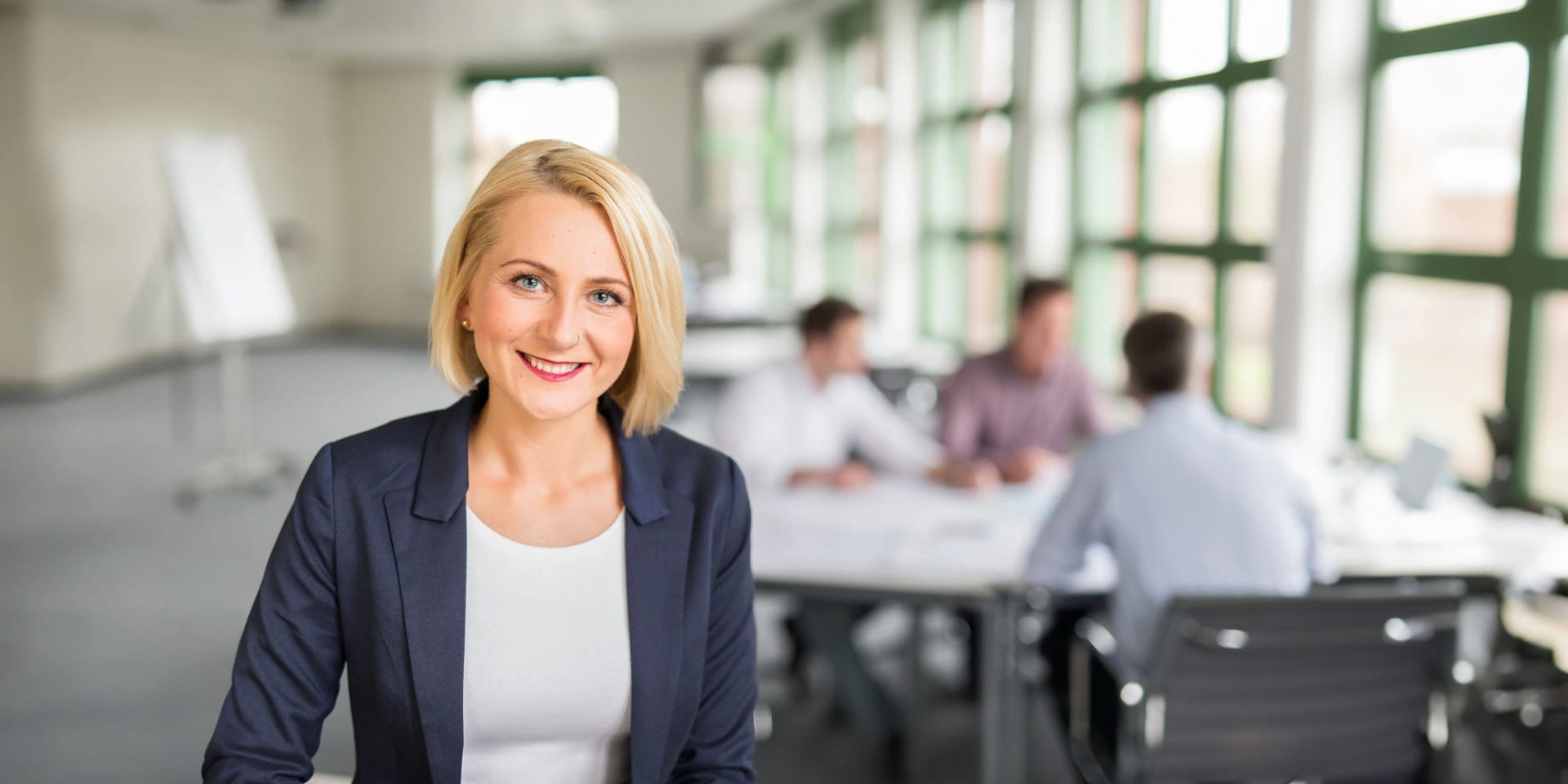 Eine Mitarbeiterin steht in einem Uniper Büro vor einem Besprechungstisch mit drei Mitarbeitern. 