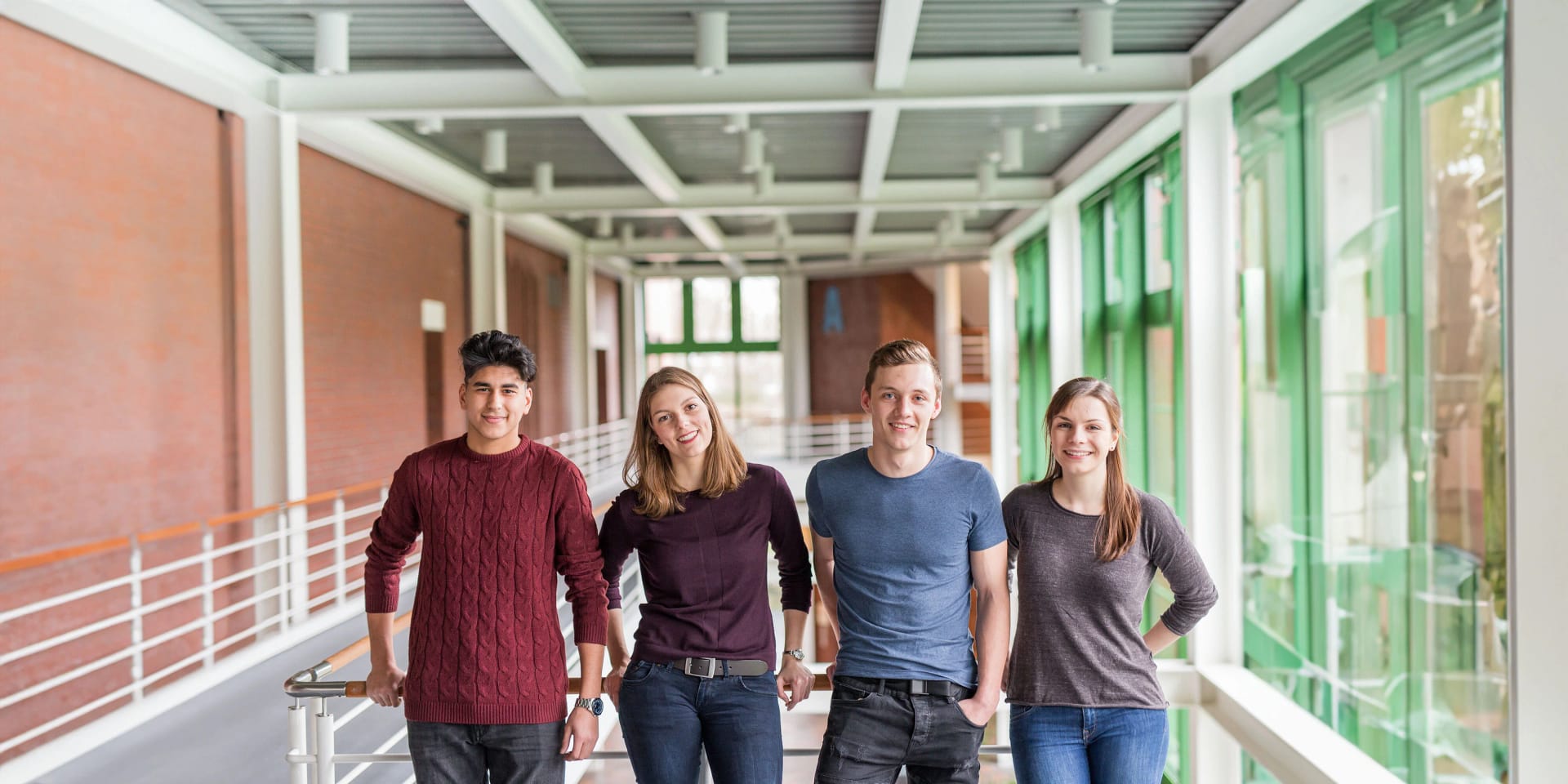 Zwei männliche und zwei weibliche Auzubildende von Uniper stehen im Flur an einem Geländer.