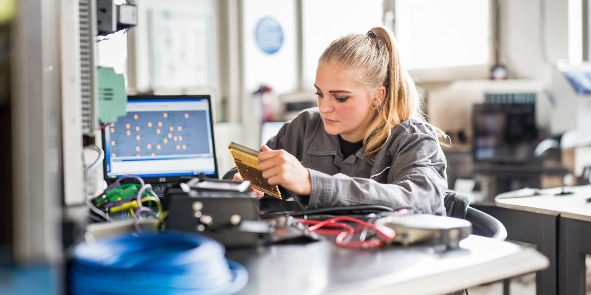 Eine weibliche Auszubildende arbeitet in der Lehrwerkstatt an einem technischen Gerät.